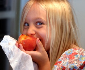 Girl enjoying peach on the low oxalate diet.